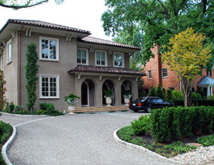 The right direction. The curve in the driveway downplays the service entrance to the left. Cobblestone inlay gently guides you to the front of the house. The columnar sweetgum lends a Mediterranean accent.