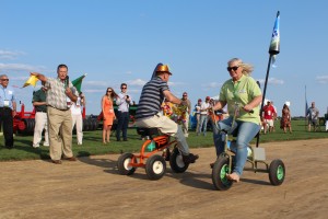Wendy Davey of Victoria, Australia competes tricycles past Claus Zander from Ontario, Canada. TPI President Eddie Keeven point to the finish line.
