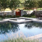 The stone wall, custom mahogany gate and Natchez Crape Myrtles blend together to form a visually pleasing yet functional separation between the pool area and the driveway.