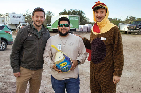 Gobble, gobble! At Summit Landscape and Design, Hondo, Texas, the company president, Josiah Peterson (left), gets the help of a feathered friend to hand out turkeys to his employees in honor of the Thanksgiving holiday. (Photo: Summit Landscape and Design)