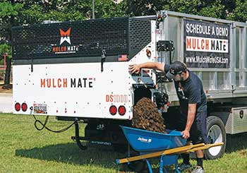 Person filling wheelbarrow using Mulch Mate (Photo: Mulch Mate)