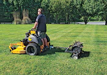 Person using tow-behind aerator (Photo: Mulch Mate)