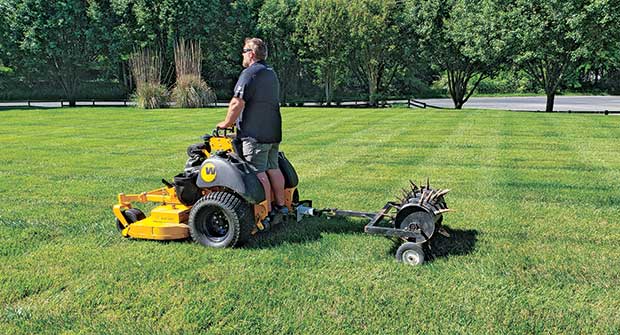 Person using tow-behind aerator (Photo: Mulch Mate)