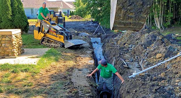 Crew members working with tracked machine (Photo: Turf Management Services)