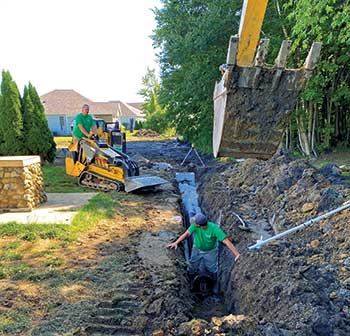 Crew members working with tracked machine (Photo: Turf Management Services)