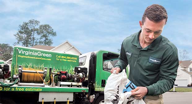 Crew member pouring fertilizer into spreader (Photo: Tony Ventouris)
