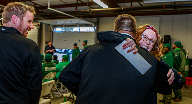 Ruppert employee Taylor Feary hugs branch manager Dave Sharry after receiving bonus check. (Photo: Ruppert Landscape)