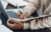 a person holding a pen and writing on a notebook (Photo: PeopleImages / iStock/Getty Images Plus / Getty Images)