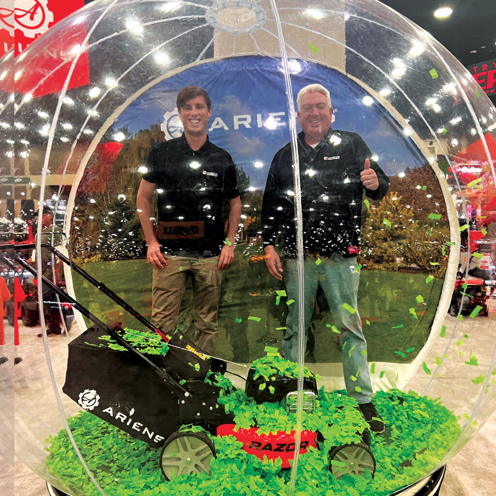 Is this holiday card worthy?: Nathan Mader (left) and Jones took Ariens up on this photo opportunity and jumped in their snow globe, complete with an Ariens mower and green confetti. (Photo: LM staff)