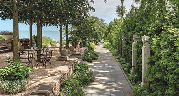 Classic pea gravel was used to ground the bosque, and a set of Four Seasons sculptures line the bluestone walkway connecting the front and back of the home. (Photo: Mariani Landscape)