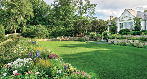 The home now overlooks vertical transitions supported by the stone wall garden terraces, lawn panel and bluff garden. Past the perennial border is the pool area and beach. (Photo: Mariani Landscape)