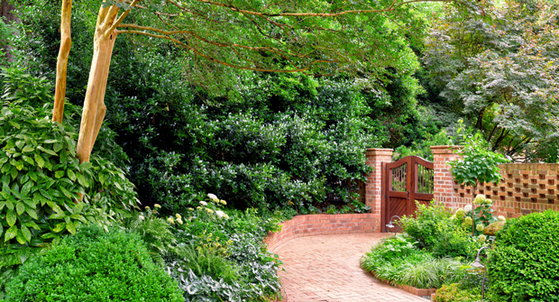 The gated entrance into the backyard is designed to feel like a natural paradise, and the Myatt team thoughtfully installs new plantings to keep the beds full, lush and eye-catching throughout the year. (Photo: Myatt Landscaping and Construction)